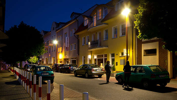 Lidé chodí v noci po ulici pod osvětlením komunikací společnosti Philips 