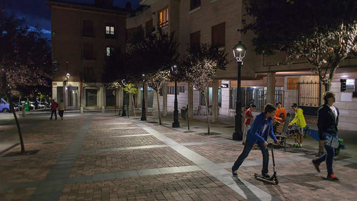 Děti si hrají v noci na náměstí pod osvětlením společnosti Philips