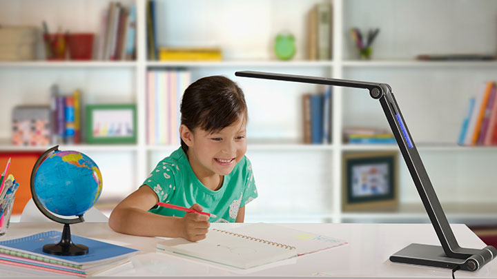 Dívka dělá domácí úkol pod stolním LED světlem Philips