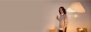 "Žena nastavuje inteligentní stmívač, ovládá teplé prostředí LED osvětlení v moderním obytném prostoru s minimalistickým dekorem"
