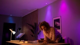 Chytrá LED světla Philips Hue vytvářejí zářivou fialovou a růžovou atmosféru v obývacím pokoji a představují přizpůsobitelné náladové osvětlení pro filmové večery a relaxaci v moderních domovech.