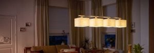 Moderní závěsné svítidlo LED s několika látkovými stínidly osvětluje útulný obývací pokoj a představuje energeticky úsporné a stylové řešení domácího osvětlení pro večerní pohodu.