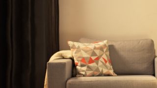 "Útulný obývací pokoj s moderní LED stolní lampou, svítící šedou sedací soupravou a vytváří teplou atmosféru pro domácí odpočinek."