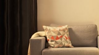 Útulný obývací pokoj s moderní LED stolní lampou, osvětlující šedou sedací soupravu a vytváří teplou atmosféru pro domácí relaxaci.